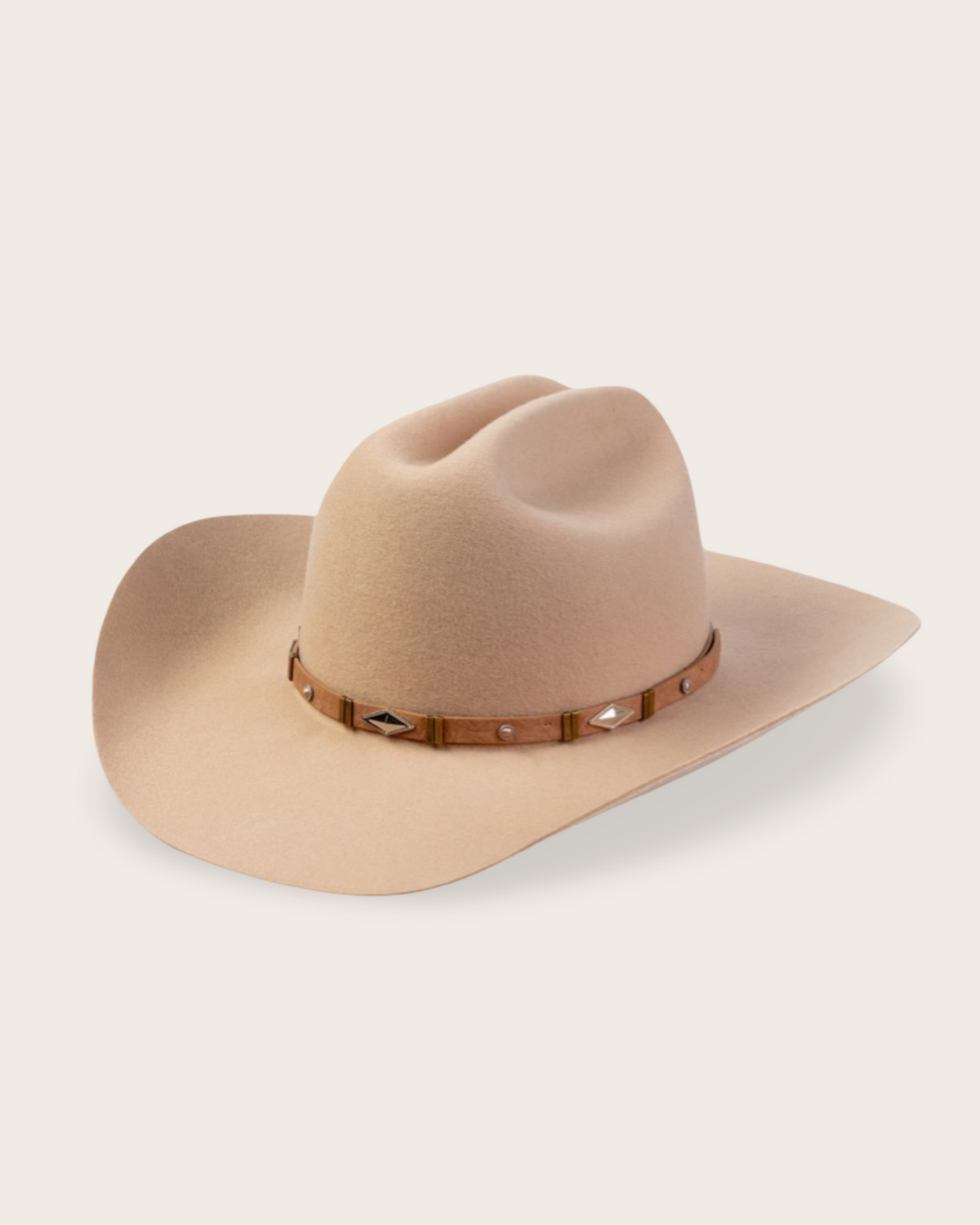 A light beige felt cowboy hat with a brown leather band decorated with small metallic studs and geometric accents, shown on a solid off-white background.